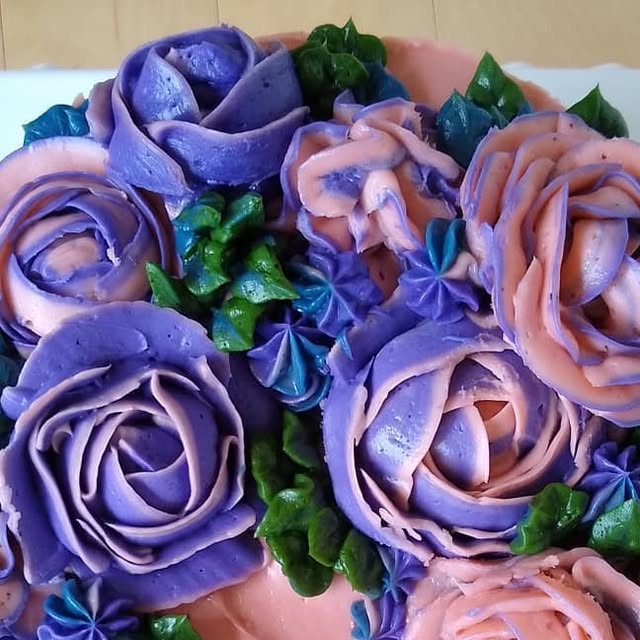 Devil's food cake covered with piped roses in violet and pink